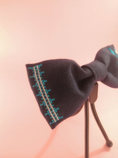 Dark blue bow with a flower vine pattern on one side and an ornament on the other