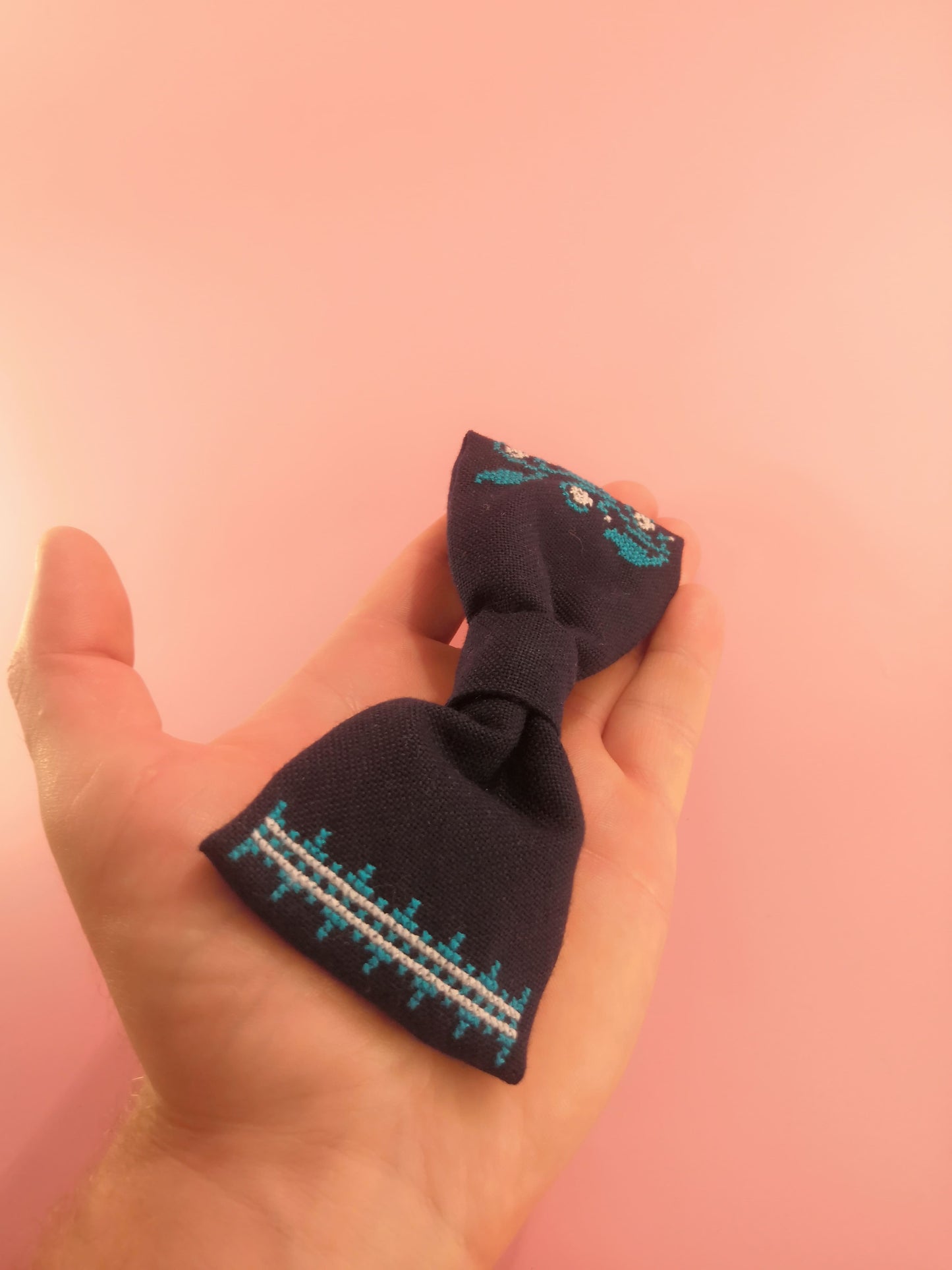 Dark blue bow with a flower vine pattern on one side and an ornament on the other