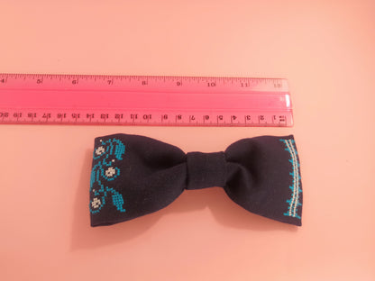 Dark blue bow with a flower vine pattern on one side and an ornament on the other