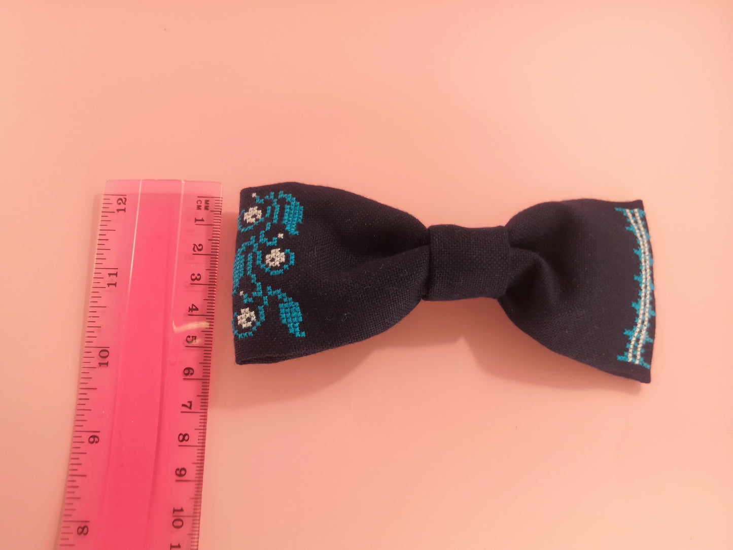 Dark blue bow with a flower vine pattern on one side and an ornament on the other